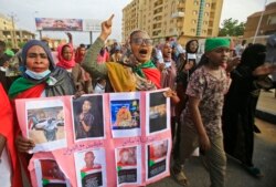 Sudanese women hold a banner bearing pictures of killed protesters during a demonstration called for by the Sudanese Professionals Association (SPA) to denounce the July 29 Obeid killings, in the capital Khartoum, Aug. 1, 2019.