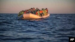 Des migrants et des réfugiés de différentes nationalités africaines attendent sur un bateau pneumatique surpeuplé, alors que les travailleurs humanitaires de l'ONG espagnole Open Arms les approchent dans la mer Méditerranée, dans les eaux internationales, le 21 février 2021.