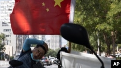 北京街头一名快递员在电动车旁休息。（2020年9月2日）