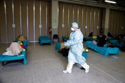 Patients lie on beds as a doctor walks past them, at a one of the emergency structures that were set up to ease procedures at the Brescia hospital, northern Italy, March 12, 2020.