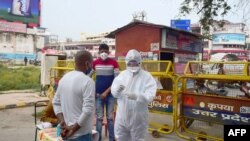 A health worker (R) wearing a Personal Protective Equipment (PPE) suit takes a swab sample from a man for a Rapid antigen tests (RATs) for Covid-19 Coronavirus, along a road in Allahabad on September 19, 2020. (Photo by SANJAY KANOJIA / AFP)