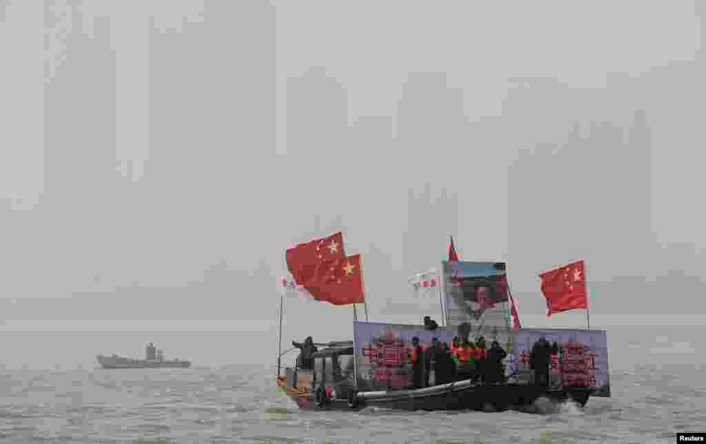Boats carrying a giant image of Mao Zedong and Chinese national flags lead winter swimmers in the Yangtze River to celebrate the 120th birth anniversary of Mao in Wuhan, Hubei province, Dec. 26, 2013. 