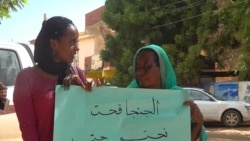 Nahid Bustami shares her protests sign with another woman (E. Sarai/VOA)