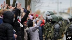 Demonstrators stand with their hands up in front of riot police line during an opposition rally to protest the official presidential election results in Minsk, Belarus, Nov. 1, 2020.