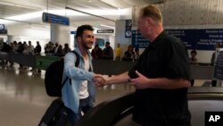 Michael White, mornarički veteran koji je nekoliko godina bio u zatvoru u Iranu zbog optužbi za špijunažu, rukuje se s iranskim političkim aktivistom Mahdijem Vatankhahom na međunarodnom aerodromu u Los Angelesu.