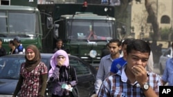 Egyptians cover their faces to avoid tear gas vapor as they walk at the site of clashes between protesters and anti-riot policemen near the Israeli Embassy in Cairo, Egypt, Sept. 10, 2011.