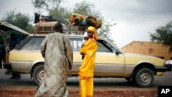 Une famille malienne attend un taxi à un barrage sur la route Gao à l'extérieur de Sévaré , à 620 kilomètres au nord de la capitale du Mali Bamako, le 27 Janvier 2013.