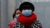 FILE - Women wearing masks make their way amid the heavy haze in Beijing.