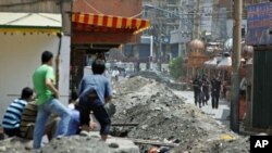 Ethnic Uighurs look on as Chinese security forces stand by the entrance to the Uighurs neighborhood in Urumqi in China's Xinjiang autonomous region, July 8, 2009 (file photo)