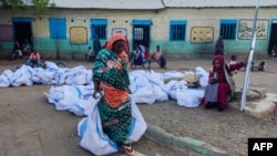 Une femme déplacée porte des sacs de l'aide humanitaire dans un camp à Gadaref, le 12 mai 2024.