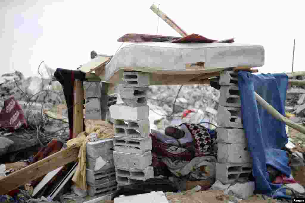 During a 72-hour truce, a Palestinian man rests inside his makeshift shelter next to the remains of his house, which witnesses said was destroyed in an Israeli offensive during in Khan Younis, the southern Gaza Strip, Aug. 13, 2014.