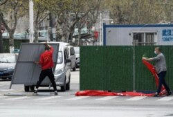 Workers wearing face masks remove barriers on a street in Wuhan, the epicentre of the coronavirus outbreak, as the city has started to loosen its lockdown, in Hubei province, China, March 21, 2020.
