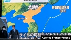 Pedestrians walk past a screen displaying a map after North Korea fired what appeared to be a ballistic missile into the sea off its east coast according to South Korea and Japan, during a news broadcast at Akihabara district in Tokyo on Jan. 5, 2022.