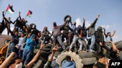 Les manifestants palestiniens brandissent leur drapeau national à l’arrière d’un camion à la frontière entre Israël et Gaza, le vendredi 27 avril 2018