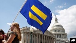 A supporter of LGBT rights holds up an "equality flag" on Capitol Hill in Washington, July 26, 2017, during an event held by Rep. Joe Kennedy, D-Mass., in support of transgender members of the military, in response to President Donald Trump's declaration that he wants transgender people barred from serving in the U.S. military "in any capacity," citing "tremendous medical costs and disruption."