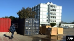 Un policier libyen inspecte les dégâts causés par un missile, sur le parking de l'hôpital général de Khadra, dédié au traitement des personnes infectées par le coronavirus (COVID-19), dans la capitale Tripoli le 9 avril 2020.