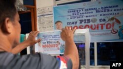 ทางการหมู่บ้านในฟิลิปปินส์ แปะป้าย "ห้องมรณะ" ที่มีตู้ฆ่ายุงที่ชาวบ้านนำมาส่งให้ทางการ ภายใต้โครงการ "เปโซแลกยุง" เพื่อกำจัดยุงที่เป็นพาหะของไข้เลือดออก 19 ก.พ. 2025 (Photo by Ted ALJIBE / AFP)