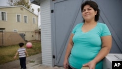 FILE - Central American refugee Roxana Janet Castillo poses for a photo at her home in Los Angeles, Dec. 10, 2015. Castillo applied for the Central American Minors (CAM) Refugee/Parole Program to bring her three children legally from her native El Salvador as refugees or with a humanitarian parole. Her son is at left.