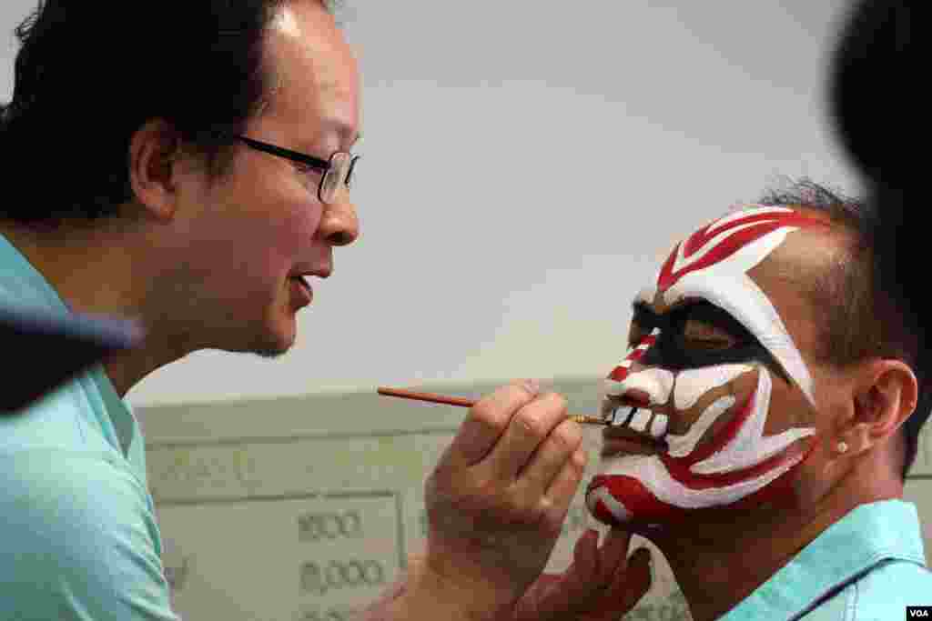 បុរស​​ម្នាក់ឲ្យគេ​​គូរ​មុខ​យក្ស លើ​​មុខរបស់ខ្លួន។ (ចាប ចិត្រា/VOA)