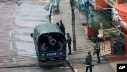 Police security forces stand by inside a police vehicle and on the sidewalk of Hledan Road in Kamayut township in Yangon, Myanmar Friday, April 16, 2021. 