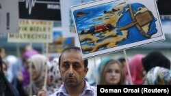 A man holds a poster with a drawing depicting drowned Syrian toddlers during a demonstration for refugee rights in Istanbul, Turkey, September 3, 2015. The distraught father of two Syrian toddlers who drowned with their mother and several other migrants a