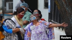 A woman mourns after seeing the body of her son who died due to COVID-19, outside a mortuary of a COVID-19 hospital in New Delhi, India, May 12, 2021.
