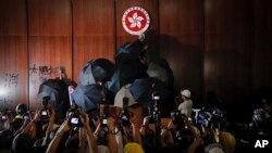 Journalists film a protester defaces the Hong Kong emblem inside the meeting hall of the Legislative Council in Hong Kong, Monday, July 1, 2019. 