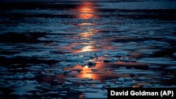 FILE- In this July 23, 2017, file photo the midnight sun shines across sea ice along the Northwest Passage in the Canadian Arctic Archipelago. The magnetic north pole is wandering about 34 miles (55 kilometers) a year.