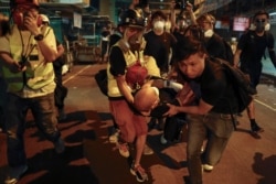 Medical staffs and protesters carry an injured man as they confront with policemen near the Shum Shui Po police station in Hong Kong on Aug. 14, 2019.