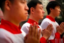 FILE - Chinese acolytes pray during a Holy Saturday Mass on the evening before Easter at the Cathedral of the Immaculate Conception, a government-sanctioned Catholic church in Beijing, March 31, 2018.