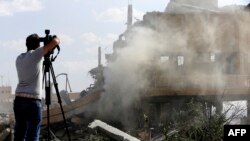 រូបឯកសារ៖ អ្នក​កាសែត​ម្នាក់​កំពុង​ថត​យក​ទិដ្ឋភាព​អគារ​រលំ​មួយ នៅ​សង្កាត់ Barzeh ប្រទេស​ស៊ីរី ថ្ងៃទី២៤ ខែមេសា ឆ្នាំ២០១៨។ 