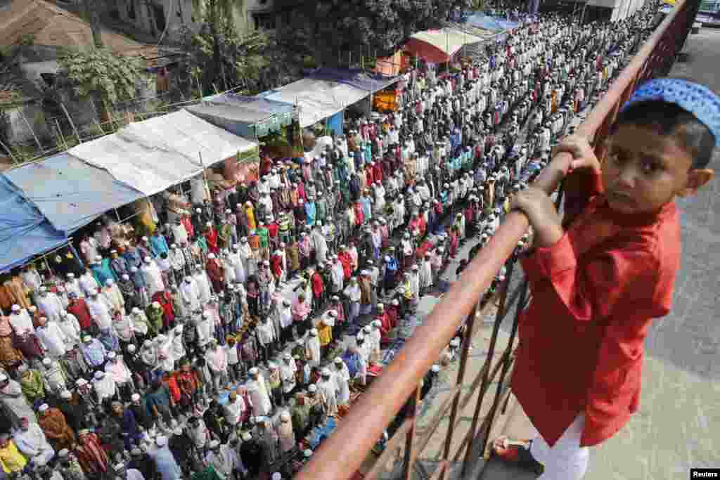 Seorang bocah laki-laki melihat orang-orang melakukan Sholat Jumat dalam acara Biswa Ijtema di Dhaka, Bangladesh. Ribuan umat Islam bergabung dalam acara tahap pertama Bishwa Ijtema (Jamaah Dunia) yang merupakan acara dimana banyak umat Islam berkumpul dengan jumlah yang mencapai terbesar kedua setelah Haji. 