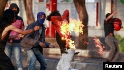 An Indonesian student protester runs after he caught fire while throwing a molotov cocktail towards police during a protest against the new president's decision to hike fuel prices this week in Makassar, South Sulawesi Province, Nov. 19, 2014. (REUTERS/Yusuf Ahmad)