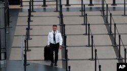 A pilot heads through the empty south security checkpoint as a statewide stay-at-home measure to stem the rapid spread of the new coronavirus remains in place at Denver International Airport, April 9, 2020.