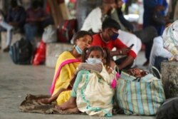 Migrant laborers wearing masks as a precaution against the coronavirus wait for transportation in Jammu, India, April 16,2021.