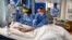 Members of the clinical staff wear personal protective equipment (PPE) as they care for a patient at the Intensive Care unit at Royal Papworth Hospital in Cambridge, on May 5, 2020. - NHS staff wear an enhanced level of PPE in higher risk areas such as cr