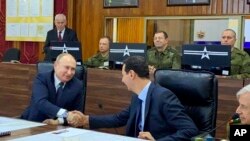 This image released by the Syrian Presidency shows Russian President Vladimir Putin, left, meeting with Syrian President Bashar Assad, center, in Damascus, Syria, Jan. 7, 2020. 