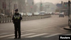 FILE - A policeman wearing a face mask stands on a road during a hazy day in Shanghai.