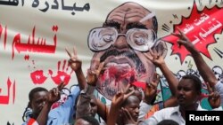 Para pengunjuk rasa meneriakkan slogan-slogan dengan membawa spanduk yang menggambarakan mantan Presiden Sudan, Omar al-Bashir, di depan Kementrian Pertahanan, Khartoum, Sudan, 19 April 2019 (foto: Reuters/Umit Bektas)