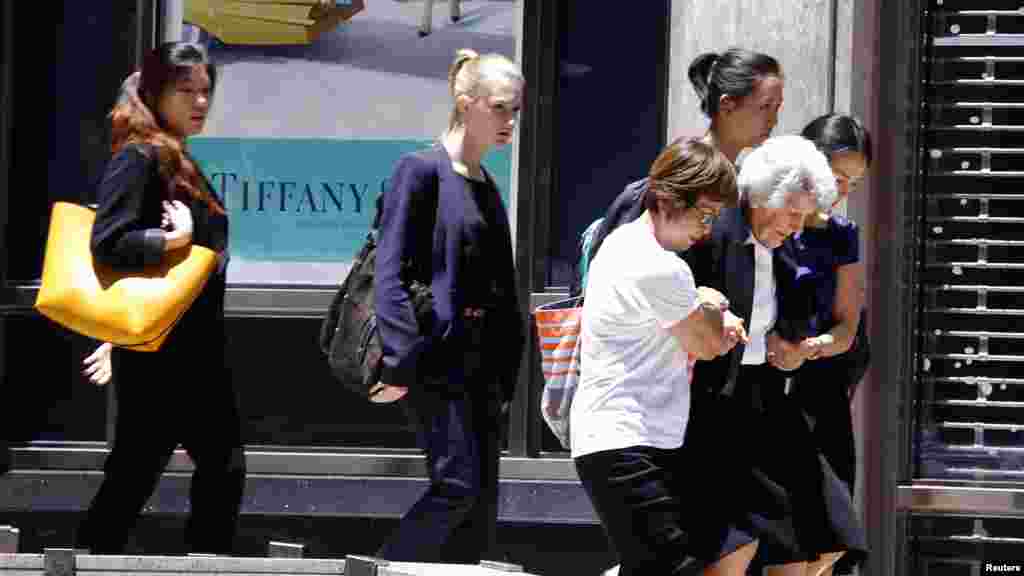 A woman is assisted as a group of people are evacuated by police from a building next to Lindt cafe in Martin Place, where hostages are being held, in central Sydney, Australia, Dec. 15, 2014. 