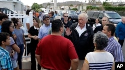 President Donald Trump and Puerto Rico Governor Ricardo Rosselló, center, listen to residents and survey hurricane damage and recovery efforts in a neighborhood in Guaynabo, Puerto Rico, Tuesday, Oct. 3, 2017. 