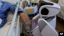 2020年4月8日意大利瓦雷泽市接受治疗的冠状病毒患者与机器人互动。