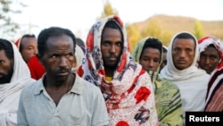 FILE - Men stand in line to receive food donations, at the Tsehaye primary school, which was turned into a temporary shelter for people displaced by conflict, in the town of Shire, Tigray region, Ethiopia, March 15, 2021.