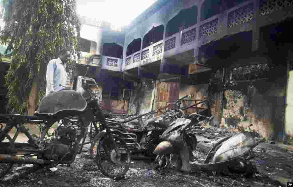 A man observes the remains of destroyed vehicles and buildings in the town of Mpeketoni, Kenya. Dozens of Somali extremists wielding automatic weapons attacked the small Kenyan coastal town for hours, assaulting the police station, setting two hotels on fire, and spraying bullets into the street killing dozens, officials said.
