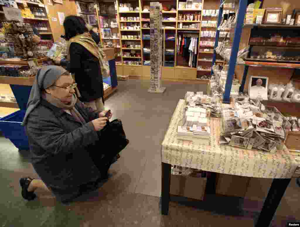 A nun takes a photograph of the first batch of souvenirs adorned with freshly-printed pictures of the newly-elected Pope Francis in a shop at the Vatican, March 14, 2013. 
