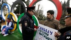 Dua polisi Rusia mendekati aktivis David Khakim (tengah kanan) yang melakukan aksi protes di Sochi, Senin, 17 Februari 2014.