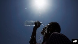Seorang pria menuangkan air ke wajahnya pada suatu hari musim panas di Hyderabad, India. (Foto: AP)
