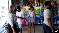 Shoppers wear masks inside a store, July 19, 2021, in Los Angeles. Los Angeles County reinstated an indoor mask mandate due to rising COVID-19 cases.