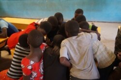 A shortage of textbooks in Malawi primary schools forces teachers to divide students into groups that share one book. (L. Masina/VOA)
