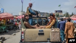 Talibanski borci u vozilu prolaze pijačnom oblašću, između tezgi i lokalnih kupaca, u Kabulu, Afganistan, 17. avgusta 2021.
